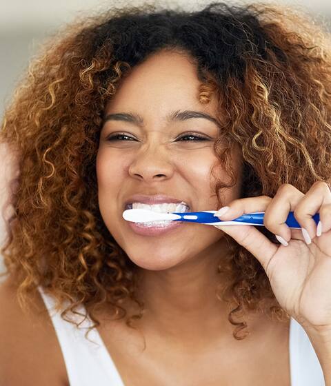 woman brushing teeth with colgate toothbrush